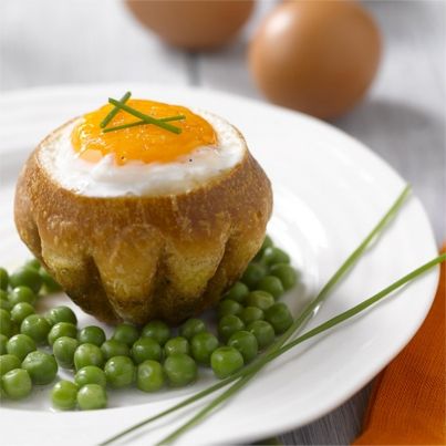 Oeuf surprise en nid de brioche sur lit de petits pois nouveaux